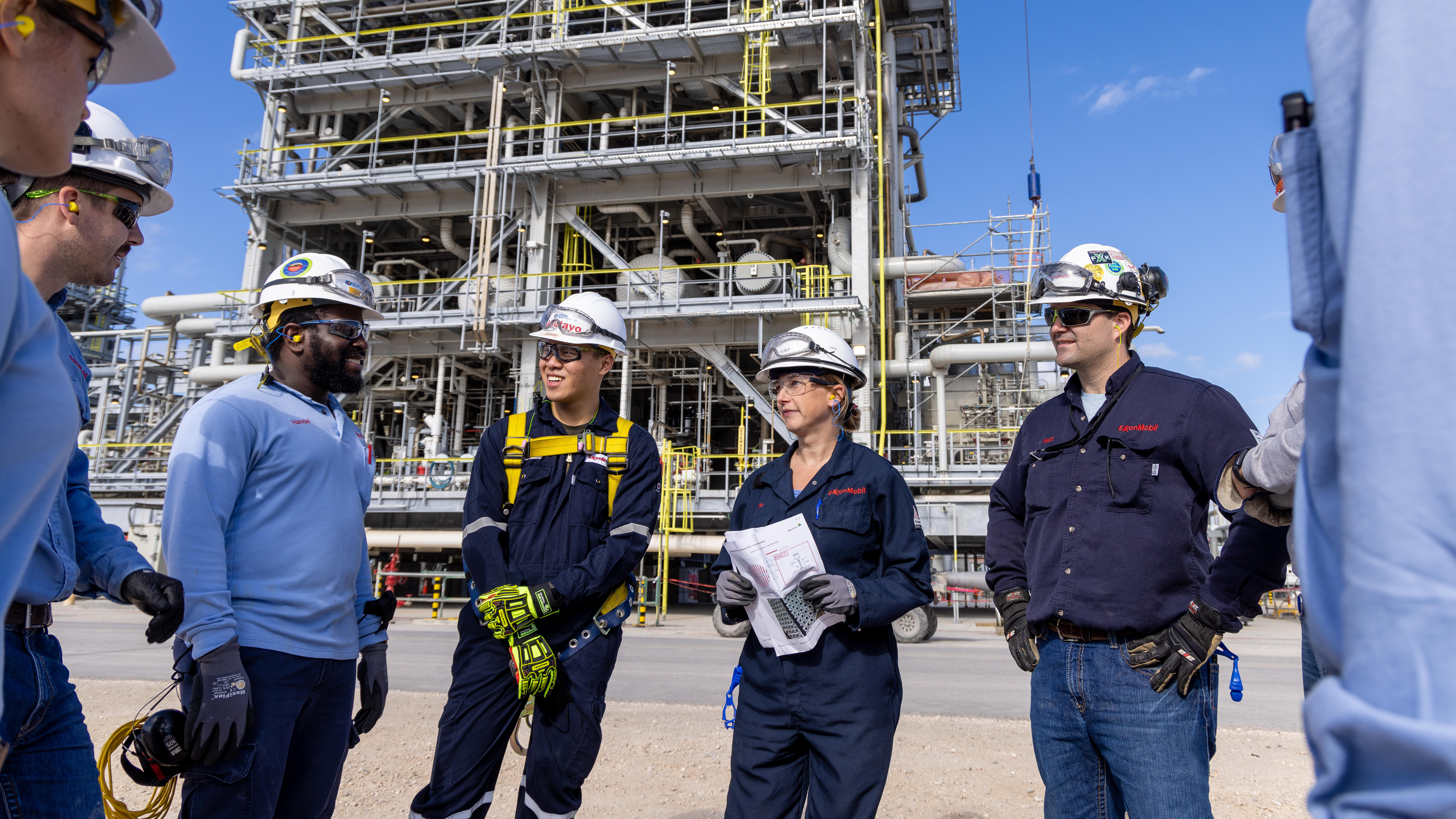 employees wearing personal protective gear at petrochemical facility having a discussion