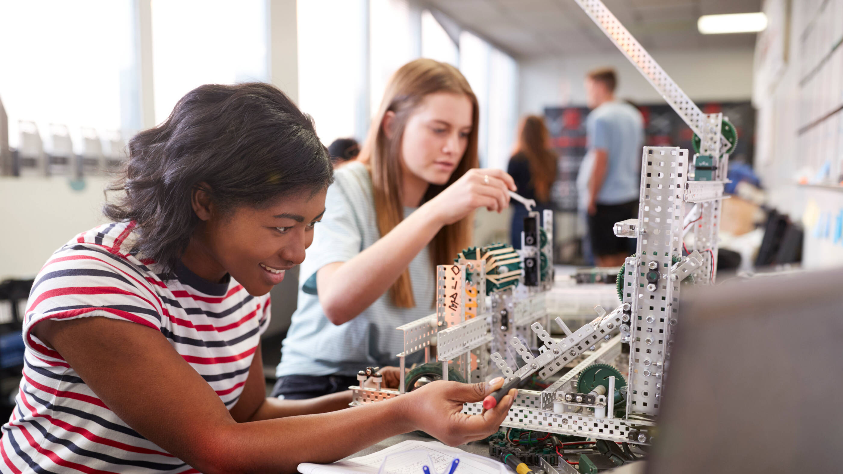 Two Female College Students Building Machine In Science Robotics Or Engineering Class