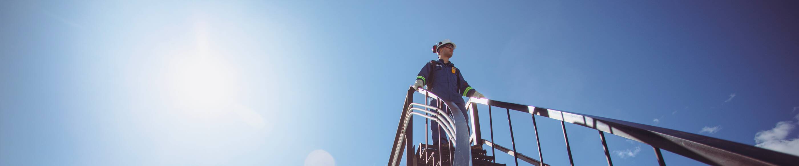 ExxonMobil employee wearing a hard hat walking down the stairs at a facility.