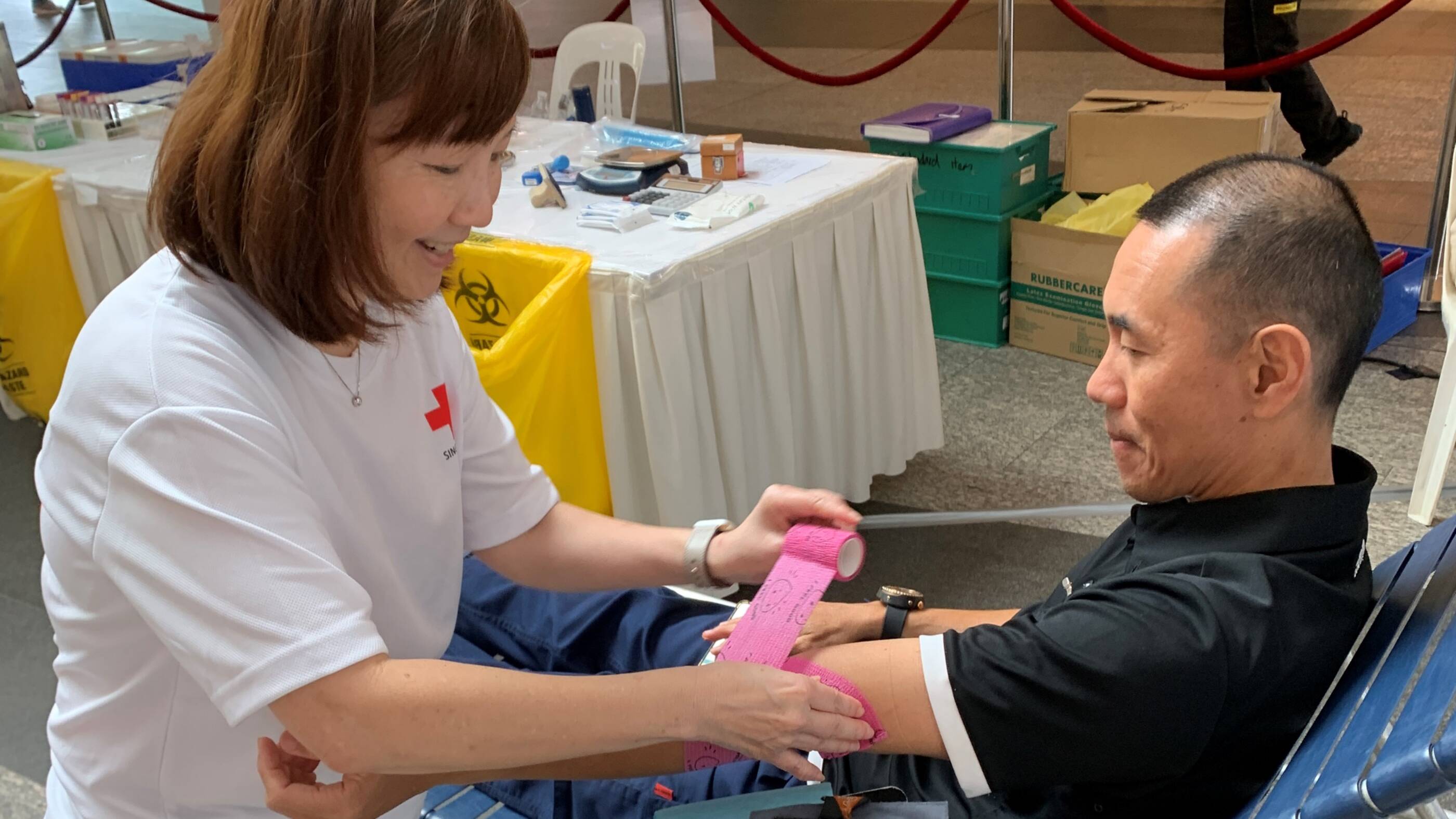 EM colleague Elsie Tan (left) bandaging the arm for EM donor Dan Yap at the ExxonMobilSG drive on Mar 27, 2025