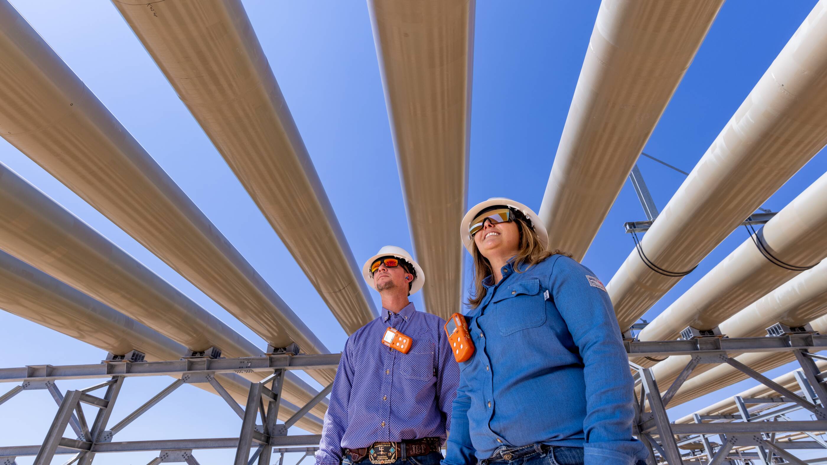 Workers standing under pipes.